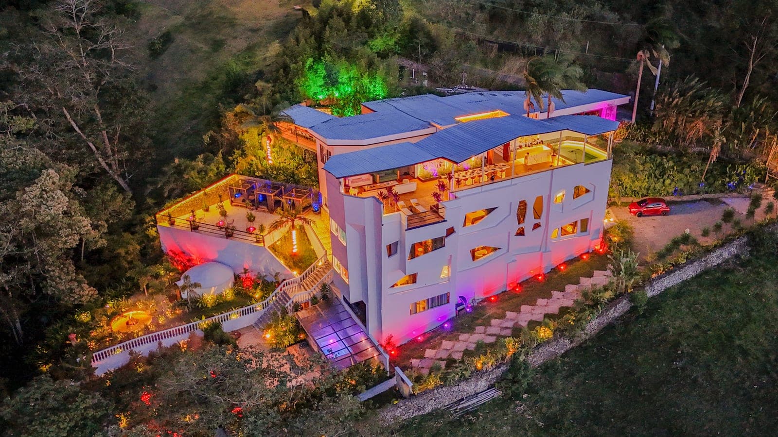 Casa de varios niveles iluminada al anochecer, vista desde un dron, editada
